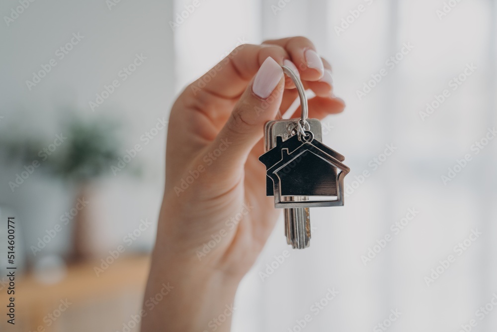 Wall mural Key to new house. Close-up female hand hold keys. Real estate agent offers flat. Sale of housing