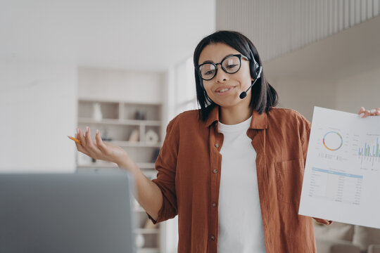 Businesswoman in glasses, headset, discuss business project online by video call showing infographic