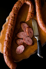 Basket with sausages and greens. Meat products. Bacon, sausage and ham in a basket with vegetables on a black background. 