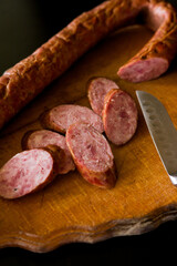 salami on board. Basket with sausages and greens. Meat products. Bacon, sausage and ham in a basket with vegetables on a black background. 