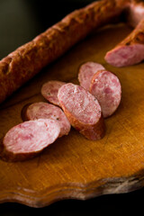 salami on a board. Basket with sausages and greens. Meat products. Bacon, sausage and ham in a basket with vegetables on a black background. 