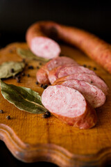salami on wooden board. Basket with sausages and greens. Meat products. Bacon, sausage and ham in a basket with vegetables on a black background. 