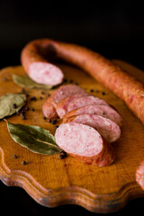 Basket with sausages and greens. Meat products. Bacon, sausage and ham in a basket with vegetables on a black background. 