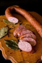 salami and sausage. Basket with sausages and greens. Meat products. Bacon, sausage and ham in a basket with vegetables on a black background. 