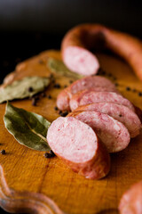 meat and sausage. Sausage cut into slices on a wooden board. Homemade sausage. Tasty and juicy hot smoked sausage. Pieces of sausage on a black background.