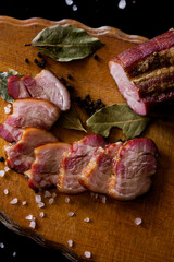 Meat on a plate. Smoked meat on a wooden board. Sliced ham on a plate. Sliced ham and bacon. Ham and salami. Pieces of chopped bacon.