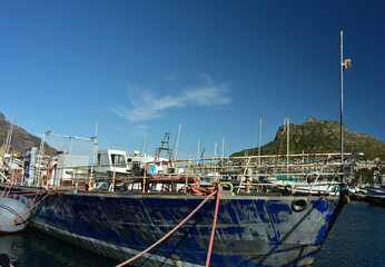 A weathered trawler in Hout Bay harbor in the Western Cape South Africa with the Sentinel peak in...