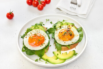 Bread with fried eggs, avocado and greens