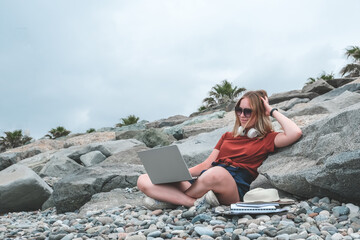 Remote work.Girl freelancer works remotely on the seashore.workation, remote work,WFVH,Van Life vibes work from vacation home,work travel,remotely work.Travelling