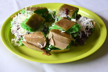 Martabak Manis Pandan Ketan Hitam or Pandan Sweet Pancake Filled with Black Glutinous Rice and Grated Coconut. Traditional Indonesia Street Food. Served on green plate. 