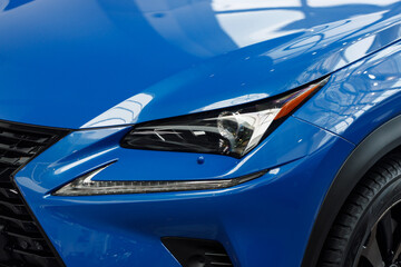 Close-up headlights of a modern blue color car. Detail on the front light of a car. Modern and expensive car concept. The car is in the showroom. Automotive concept. Classic blue color. LED light