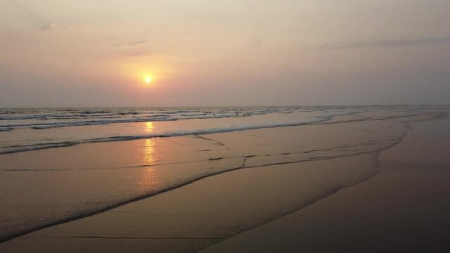 Aerial View of the Sunset with Silhouettes of People in the waves on the beach in Cox's Bazar, Bangladesh