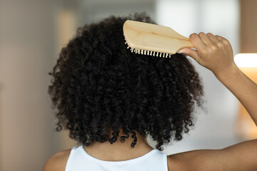 Rear view of a lady combing her hair with a wooden comb. Selective Focus