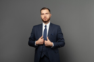 Smart brunette man wearing formal clothes looking at camera on grey background