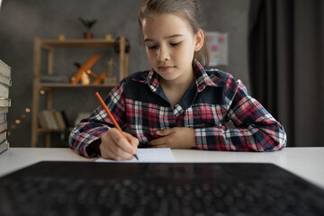 caucasian child girl have fun drawing studying online on computer from home, using laptop at home,...