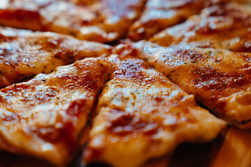 toasted cheese pizza cut into pieces on a wooden round cutting board. traditional treats for the party. Italian cuisine.