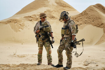 Military soldier team in uniform with armforce in middle east desert battle field standing discussion 
