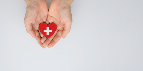 The national flag of Switzerland of arms in female hands. World red cross day. Flat lay, copy space.