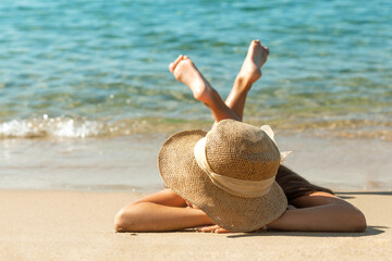 Sea Holiday on Sandy Beach Sea coast. Girl in sun hat sunbathing on tropical beach. Blue Sea Background - obrazy, fototapety, plakaty