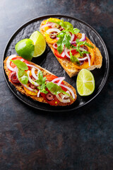 Vegetarian sandwiches on a dark background. Spanish tapas with vegetables, greens, olives and lime. Healthy sandwiches on a black plate. Top view. Copy space