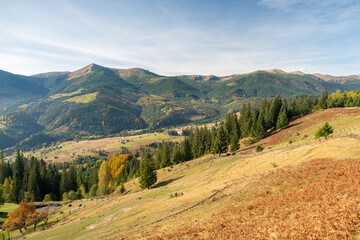 Beautiful view of autumn meadow and mountains at sunny day. Wonderful panoramic landscape under blue sky.