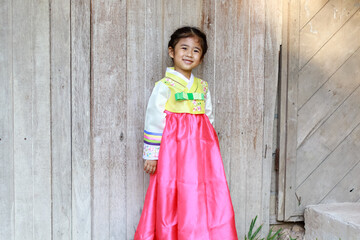 Asian children smile in national costumes. Little girl kid with Korean hanbok dress on wooden board background.
