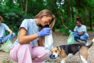Young woman with her dog waste collector busy separating medical or PPE waste from plastic garbage...