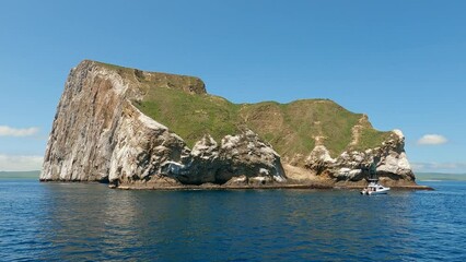 Boat sailing around the famous Kicker rock in the Galapagos islands in the Pacific ocean in Ecuador in South America. Shot with a tilt up motion