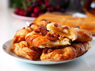 Fresh puff pastry buns with nuts. In the background are cherries, a kettle of tea.