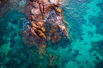 Aerial view over rocks landscape and blue turquoise sea at Costa Brava, Catalonia, Spain. Artistic summer background of the mediterranean coast. Summer conceptual background. Beach tourism vacations.