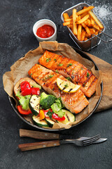 Salmon steak with vegetables on dark background.