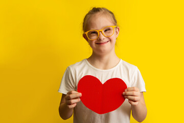 Fototapeta Girl with Down Syndrome holding a big red paper heart obraz