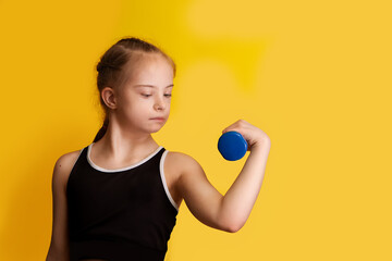 A girl with Down syndrome goes in for sports, lifting dumbbells