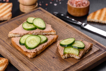 Delicious fresh sandwich with chicken liver pate with crispy toast, butter and cucumber