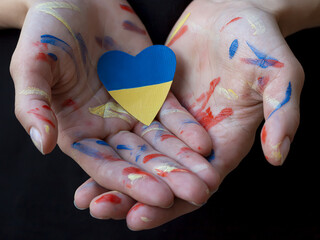 Woman hands painted colorful paints with heart colored Ukrainian flag blue and yellow colors