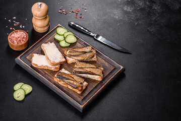 Delicious fresh sandwich with sprats with crispy toast, butter and cucumber