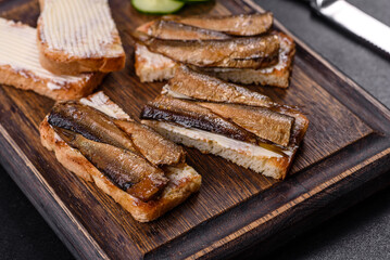 Delicious fresh sandwich with sprats with crispy toast, butter and cucumber