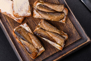 Delicious fresh sandwich with sprats with crispy toast, butter and cucumber