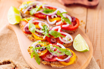 Spanish tapas and lime on a cutting board. Bruschetta with tomatoes, greens and olives. Healthy open sandwiches on wooden boards. Top view