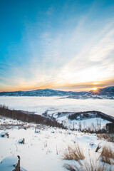 Fototapeta na wymiar Frosty morning on Skalka mountain in Beskydy mountains overlooking the valley covered with clouds and fog and a view of Lysa mountain. Snowy landscapes. Czech republic in centre of Europe