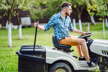 Portrait of gardener using a lawn mowing tractor for cutting grass. professional gardening details