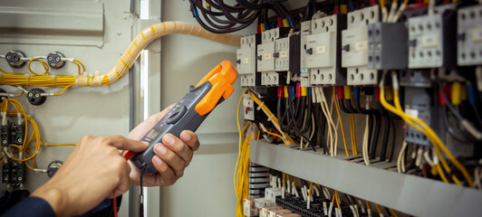 Electrical engineer using measuring equipment to checking electric current voltage at circuit...