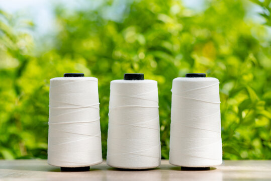 Raw White Polyester FDY Yarn spool with green blurred background