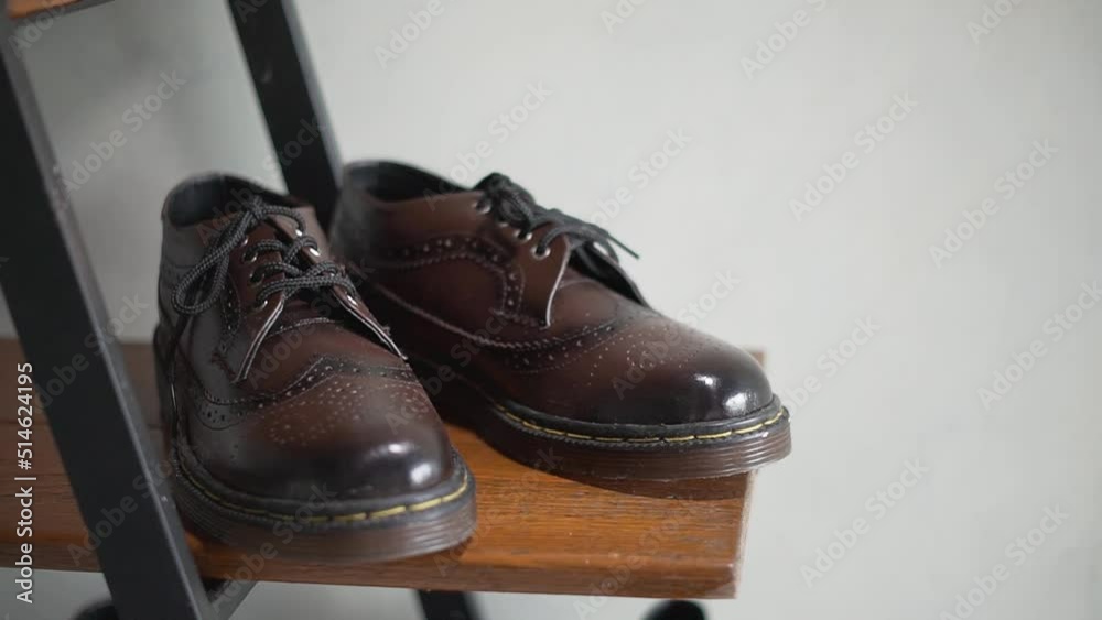 Wall mural Detail view of men's classic dark brown genuine leather wingtip brogue shoes with rubber sole on a display rack, slow motion indoor footage - Wall murals