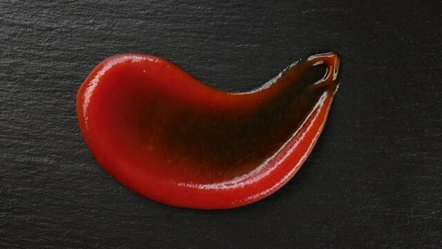 Ketchup. Draw a smile with ketchup on dark stone background