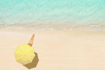 Fototapeta na wymiar Top view of woman in bikini lying and sunbathes under yellow umbrella on tropical Seychelles sea sand beach. Aerial, drone view