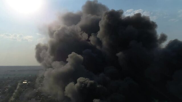 Rocket attack on the plant. Warehouse building strong fire in warehouses black smoke and fire. Shooting from a drone over a large-scale fire. Grain video. Rescuers put out a huge fire