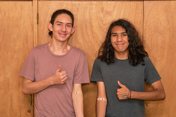 Two young men with arms covered with a patch for having donated blood.