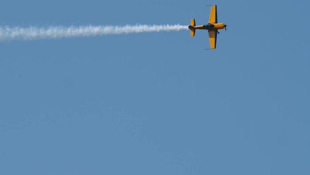 Yellow sports plane fly high in the sky performing spectacular stunts