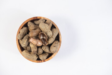 selective focus on boiled peanuts on wooden bowl isolated on white background